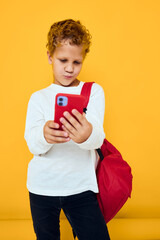 portrait of a little boy talking on the phone with a school backpack isolated background