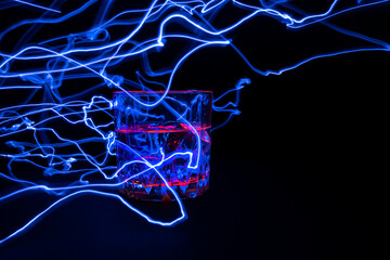 A vessel, a glass filled with a transparent liquid with an electric lightning and beating from the surface. On a black background