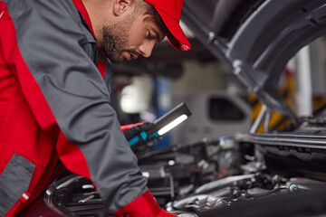 Man examining engine of vehicle