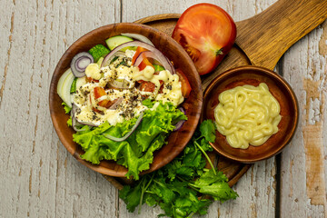 Homemade salad with dressing,cucumber, tomatoes,lettuce,shallot and cream cheese.  Rustic style. Selective Focus. Top view. Copy space. No.01