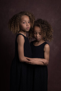 Fine art studio portrait of two sisters in dark painterly style