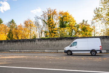 Compact mini van for commercial use and small business running on the road with autumn yellow trees...