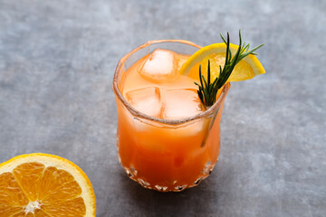 Orange juice in glass with rosemary and fresh fruits. Selective focus and blurred background.
