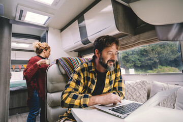 Alternative nomad lifestyle office workstation people. Man working on laptop computer inside luxury...