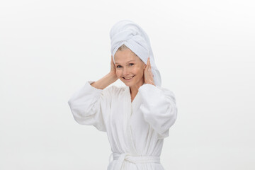 Image of joyful elderly adult woman wearing bathrobe and towel over her head smiling over white background