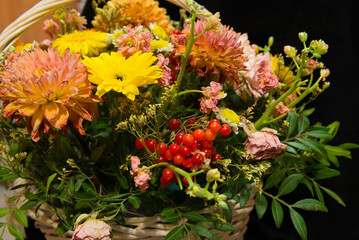 Close-up of a bouquet of beautiful flowers and red berries in a wicker basket