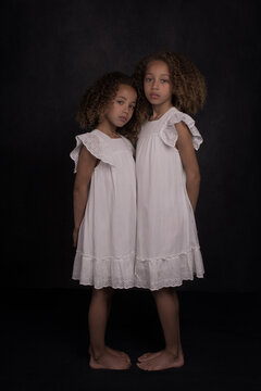 Painterly studio portrait of two little sister girls in white dress