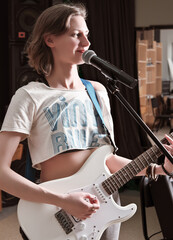 beautiful young woman guitarist performing music in studio. sound check, rehearsal, rock band learning new song.