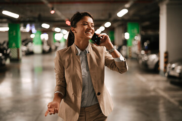 Businesswoman in suit unlocking car on parking. Beautiful woman talking to the phone..