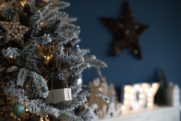 Beautiful snowy Christmas tree against blue background with beautiful ornaments for the holidays. 