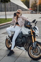 Obraz na płótnie Canvas Elegant woman biker posing in city with her motorcycle