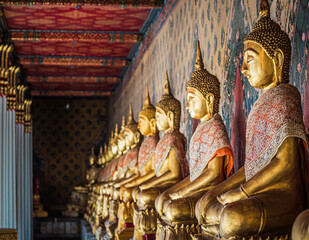 Row of Buddha image in meditation posture
 lined up at Wat Pho temple in Bangkok, Thailand.
