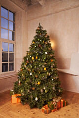 full-length Christmas tree decorated with transparent balls and a garland with warm lights and beautiful boxes with gifts under it