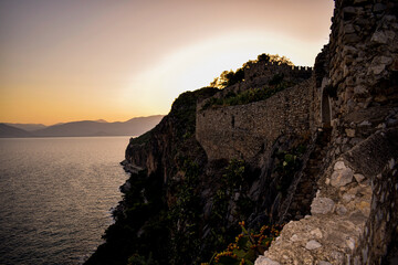 The sun sets behind the mountains against the background of the walls of the old castles