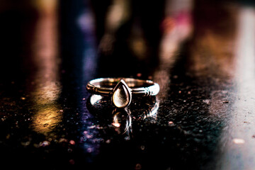 Close-up on black marble lies a silver ring with a stone
