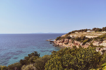 The clear blue sea splashes against the wooded cliffs