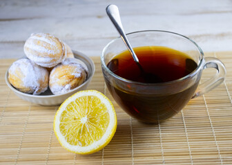 image of cookies, cups of tea, teapot with tea and lemon on a wooden table