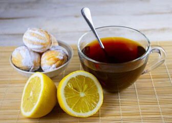 image of cookies, cups of tea, teapot with tea and lemon on a wooden table
