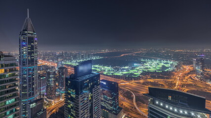 Aerial skyline with Golf Club, hotels and residential areas far away in desert in Dubai night timelapse, UAE, top view