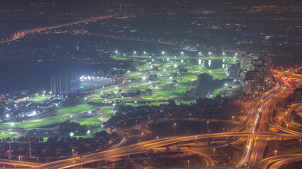 Aerial view to Golf course with green lawn and lakes, villas and houses behind it night timelapse.