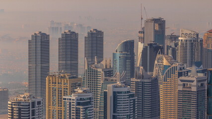 Naklejka premium JLT skyscrapers near Sheikh Zayed Road aerial timelapse. Residential buildings and villas behind