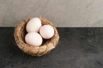 Fresh chicken eggs ( Telur Ayam Kampung ). White eggs served in bird nest with copy space. Selective focus image.
