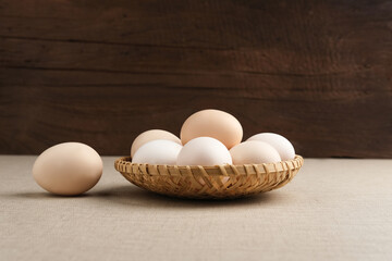 Fresh chicken eggs ( Telur Ayam Kampung ). White eggs served in bamboo plate with copy space. Selective focus image.
