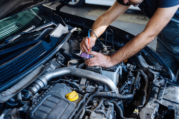 Auto service, repair, maintenance concept. Auto electrician troubleshooting a car engine.