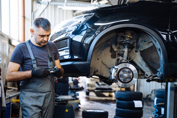 Fototapeta na wymiar ?ar service, repair, maintenance concept. Mechanic in black gloves at work in his garage.