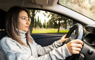 Young woman driver wandering around rural neighborhood. Driving safety and enjoyment concept.