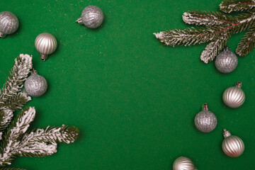 Obraz premium Christmas or New Year silver colored baubles, fir branches over green background. Greeting card. Minimal concept, copy space