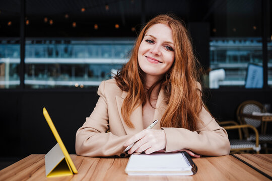 Smiling beautiful woman with diary sitting at table in cafe