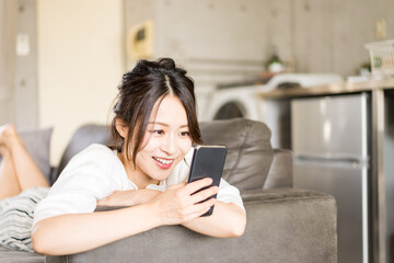 部屋でスマホを使う若い女性