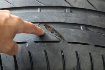 Selective focus of crack damage on tire tread with blurred finger pointing to damage on tire tread  © Nischaporn