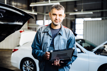 Car service, repair, maintenance concept. Engineer makes computer diagnostics of the car in autoservice. Vehicle wiring inspection.