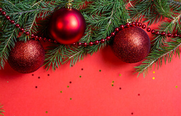 Obraz na płótnie Canvas Red background with Christmas decorations from fir branches and Christmas balls. Bright red Christmas and New Year background, Free space for your text. Natural spruce branches.