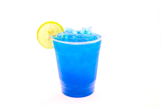 Ice cold electric blue lemonade with a slice of lemon in a disposable cup.