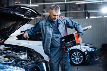 Fototapeta na wymiar Auto service, repair, maintenance concept. Electrician mechanic technician working on a garage.