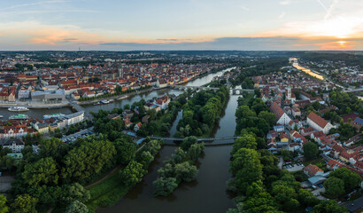 Panorama der Stadt Regensburg in Bayern mit dem Fluss Donau dem beleuchtetem Dom und der steinernen Brücke im Sommer zur blauen Stunde im Zwielicht, Deutschland