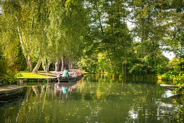 EinBoot auf einem idyllischer Kanal im Spreewald mit sich spiegelnden Bäumen im Wasser