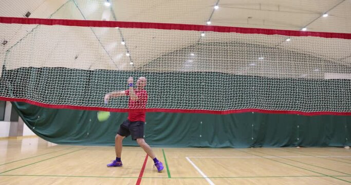Badminton - badminton courts with players competing; Badminton player beats a shuttle in the gym, learning to play badminton , exercises with shuttlecock on a badminton court