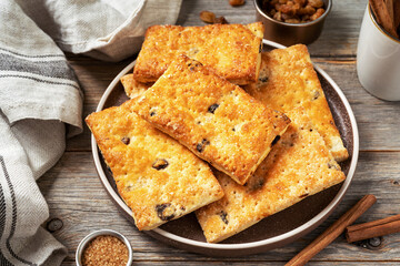 Puff dessert with raisins in a plate on a wooden light gray culinary background. Delicious homemade sweet pastries