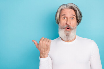 Portrait of attractive amazed grey-haired man demonstrating copy space ad direction isolated over bright blue color background