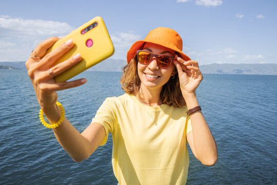 Girl travel blogger takes selfies for her social networks on a background of a picturesque Sevan Lake in Armenia