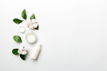 Obraz na płótnie Canvas Organic cosmetic products with cotton flower and green leaves on white background. Copy space, flat lay