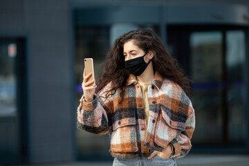Portrait of young woman wearing safety mask. Beautiful girl with face mask using mobile phone.