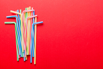 Heap of colorful plastic drinking straws on Colored background, flat lay. Copy Space for text