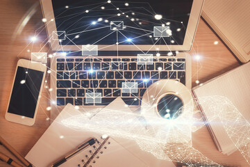 Envelop hologram drawing over computer on the desktop background. Top view. Double exposure. Technology concept.