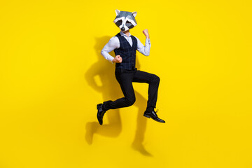 Fototapeta na wymiar Full length photo of bizarre freak anthropomorphic racoon guy jump win lottery raise fists up isolated over yellow color background