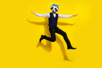 Photo of surreal absurd authentic guy racoon mask jump fly arms isolated over yellow bright color...